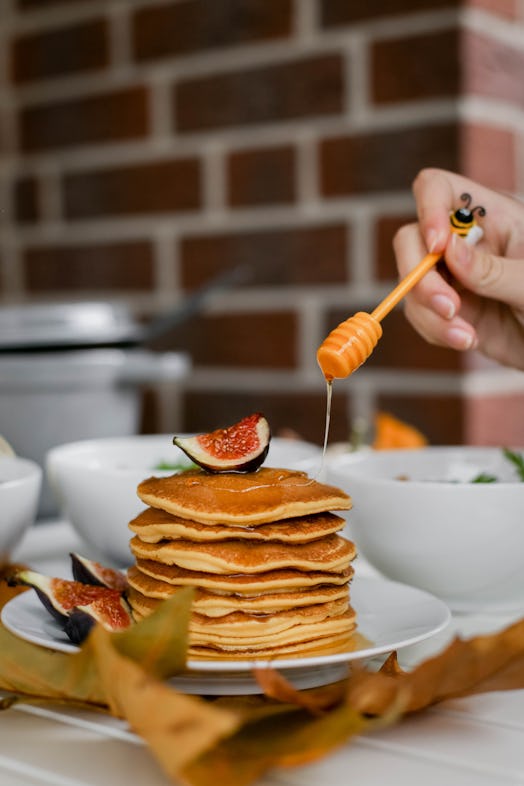 A woman pours honey on pumpkin pancakes at Thanksgiving brunch.