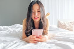 Yound woman using smart phone on the bed 