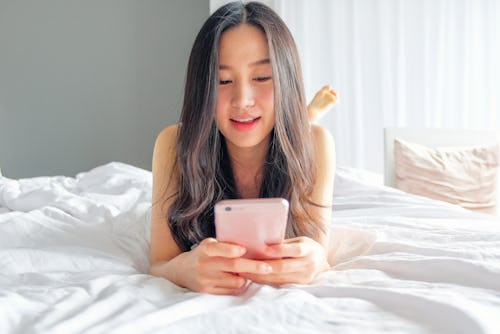 Yound woman using smart phone on the bed