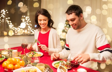 A happy couple enjoys a holiday dinner at home sitting side by side. 