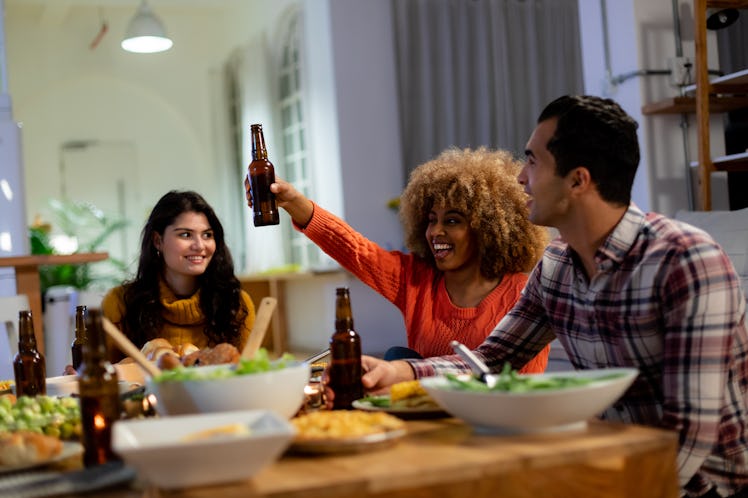 A group of friends enjoying a Thanksgiving dinner and beer in a kitchen,