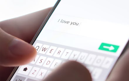 Sending I love you text message with mobile phone. Online dating, texting or catfishing concept. Rom...