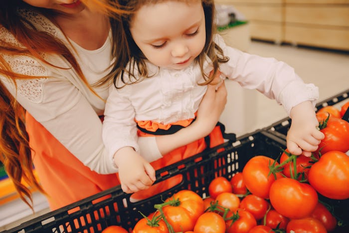 beautiful young red-haired mother with little daughter buying groceries and products in the supermar...