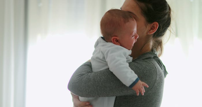 Casual real life mom consoling crying newborn baby son at home