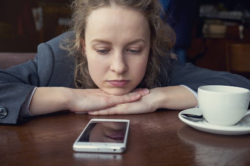 Disappointed sad woman looking at phone and waiting message or call