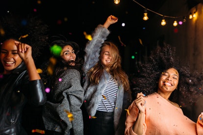 Group of female friends dancing at night under confetti