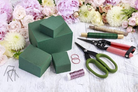Florist workplace: Rose, lisianthus, dahlia, peony and florist's accessories on wooden table.