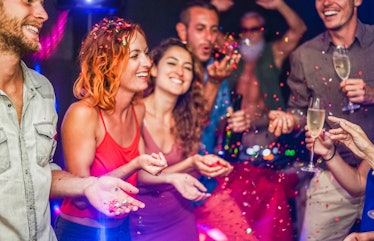 Happy friends making party throwing confetti, dancing and drinking champagne with dj mixing music - ...