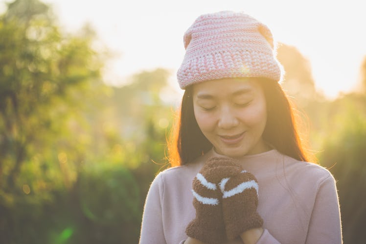 Winter and spring, Beautiful woman wearing knit sweater and gloves and earmuff, holding hands for wa...