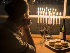Low key Image of jewish holiday Hanukkah (holiday of lights) with menorah, burning candles, donuts a...