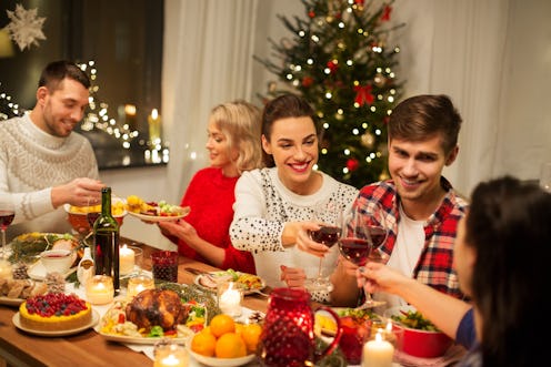 holidays and celebration concept - happy friends having christmas dinner at home, drinking red wine ...