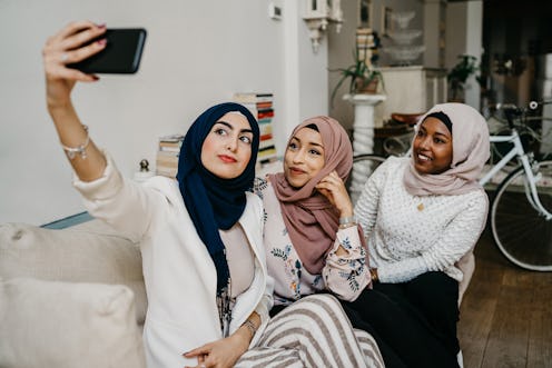 Arab friends taking a selfie on the sofa in house - Millennials in a moment of intimacy and relaxati...