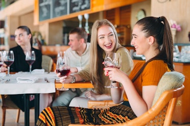 Friends have fun drinking wine, talking and smiling in the restaurant