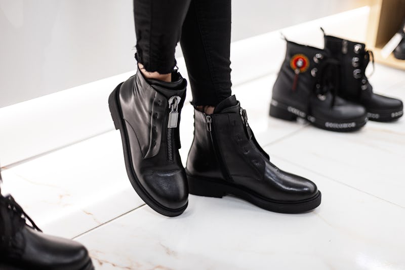 Young fashion woman in black stylish jeans in fashionable leather boots stands on the white tile in...