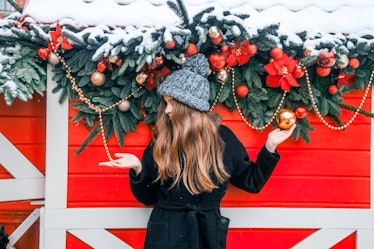 A woman in winter clothes poses with Christmas decorations in a holiday-named town.