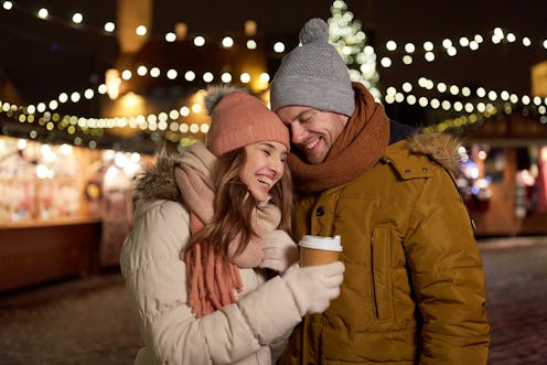 winter holidays, hot drinks and people concept - happy young couple with coffee at christmas market ...