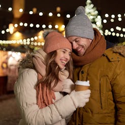 winter holidays, hot drinks and people concept - happy young couple with coffee at christmas market ...