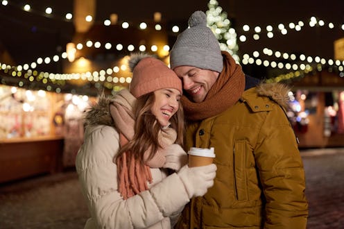 winter holidays, hot drinks and people concept - happy young couple with coffee at christmas market ...
