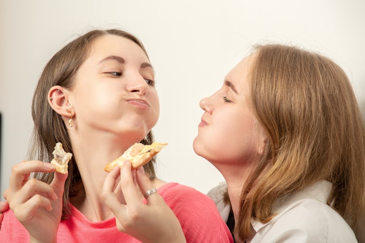 two happy girls lesbians eats pizza laughing