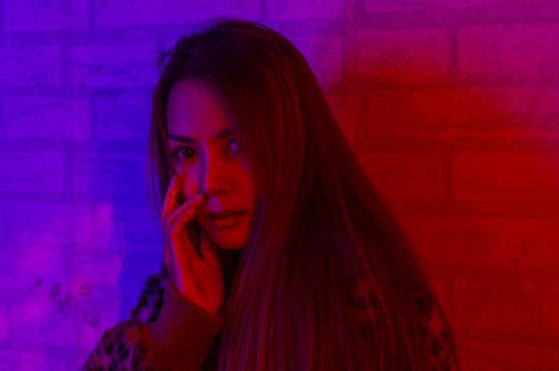 Portrait fashion of an Asian woman in neon-violet and red light  that shines in the dark with beauty...