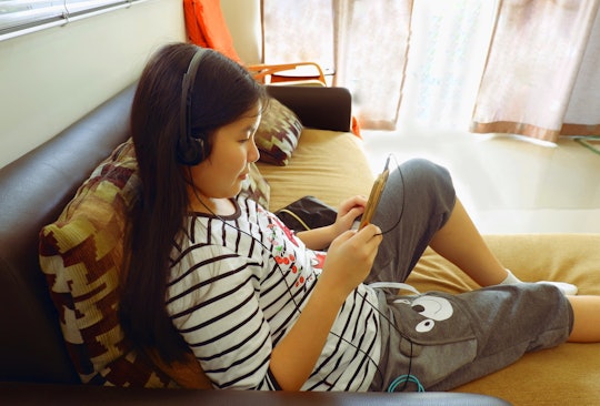 Young teen girl listening to audiobook on headphones
