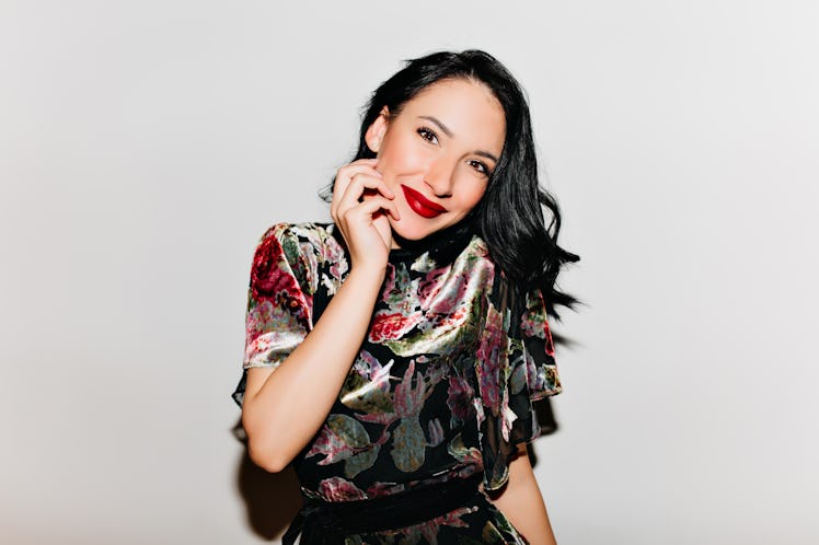 Glamorous black-haired woman with bright makeup posing with surprised smile. Glad female model with ...