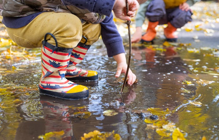 kids legs in rubber rain boots in
puddle in autumn