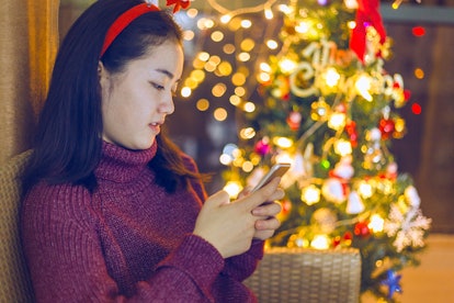 An Asian woman operates mobile devices on Christmas Eve.