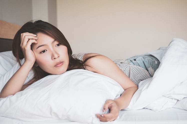 Young asian woman in sad laying on a bed