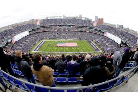 U.S. service members hold a large flag on the field at M&T Bank Stadium as part of the Baltimore Rav...