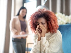 Young woman crying. Curly young woman crying while sharing her thoughts with psychoanalyst