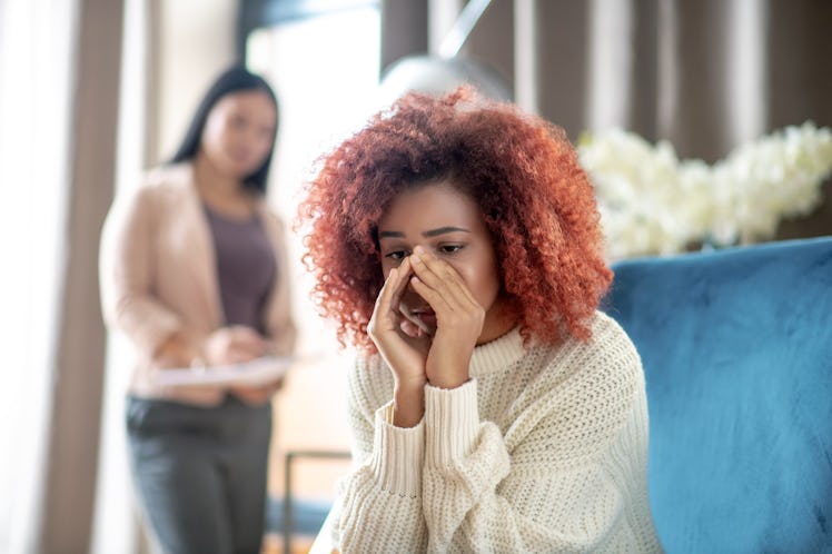 Young woman crying. Curly young woman crying while sharing her thoughts with psychoanalyst