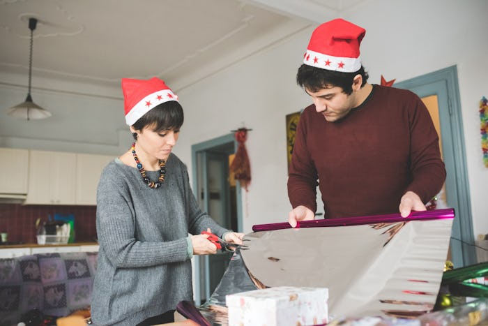 a couple wearing santa hats, wrapping presents