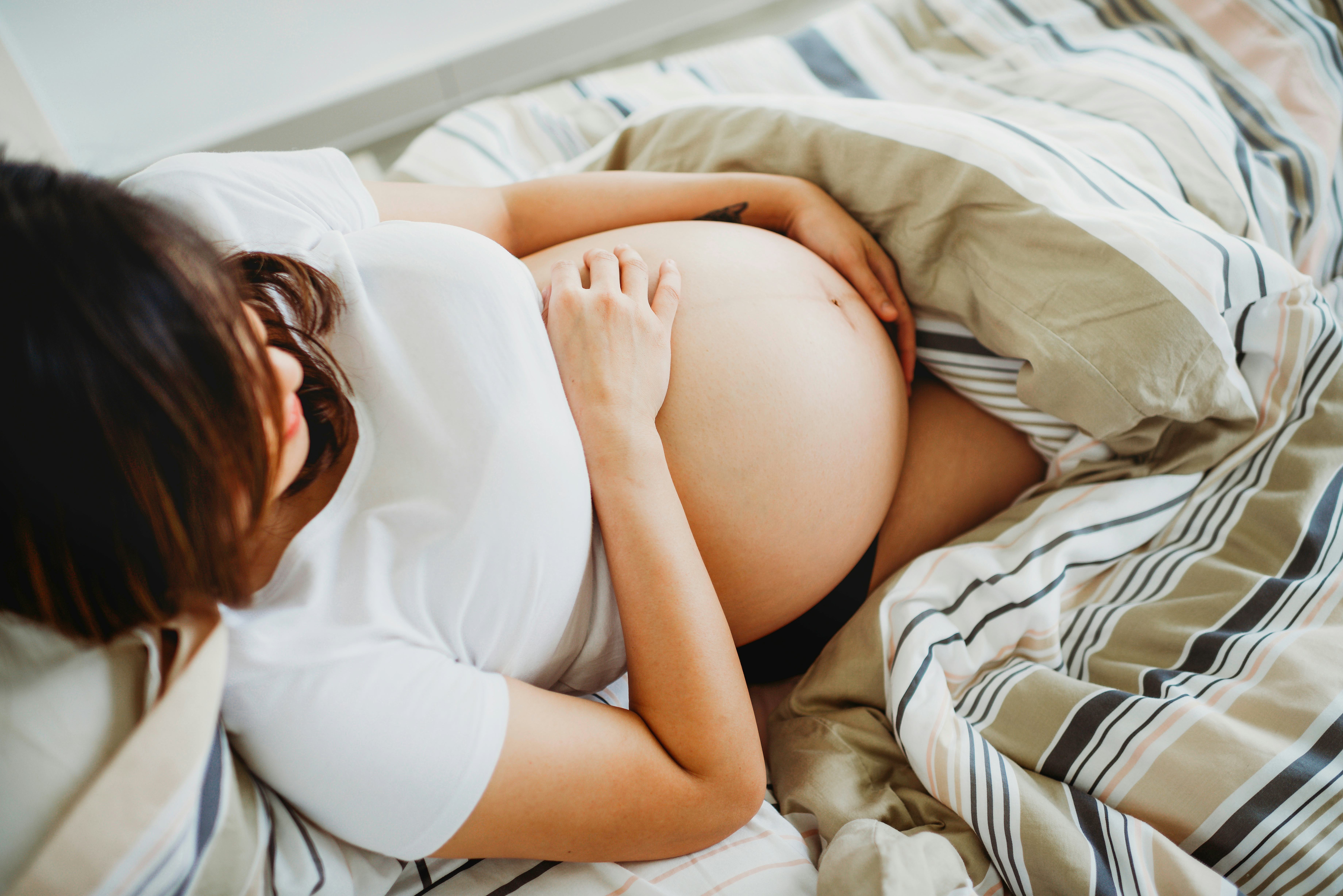 pregnant woman lying in bed with blankets
