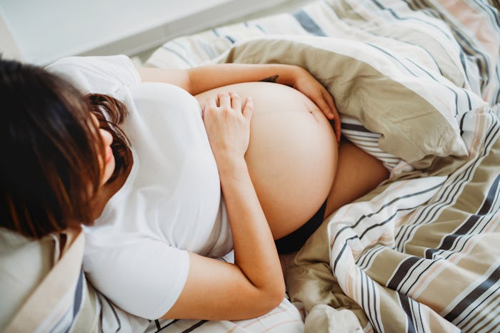 pregnant woman lying in bed with blankets
