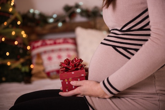 a pregnant woman holding a Christmas gift on her lap
