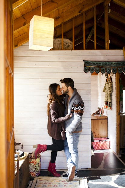 A couple shares a romantic moment while hanging out in a cabin during a winter getaway. 