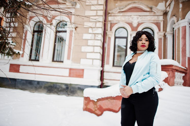 Stylish african american plus size model at streets of city on winter day.