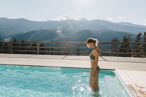 Young woman spending winter or spring vacation in luxury spa resort with swimming pool over alpine m...