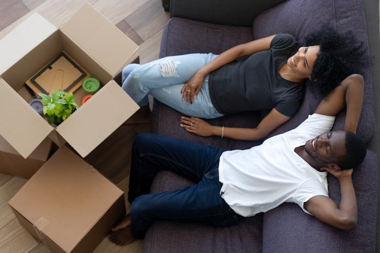 African american millennial couple relaxing on couch in new home, happy young black renters tenants ...