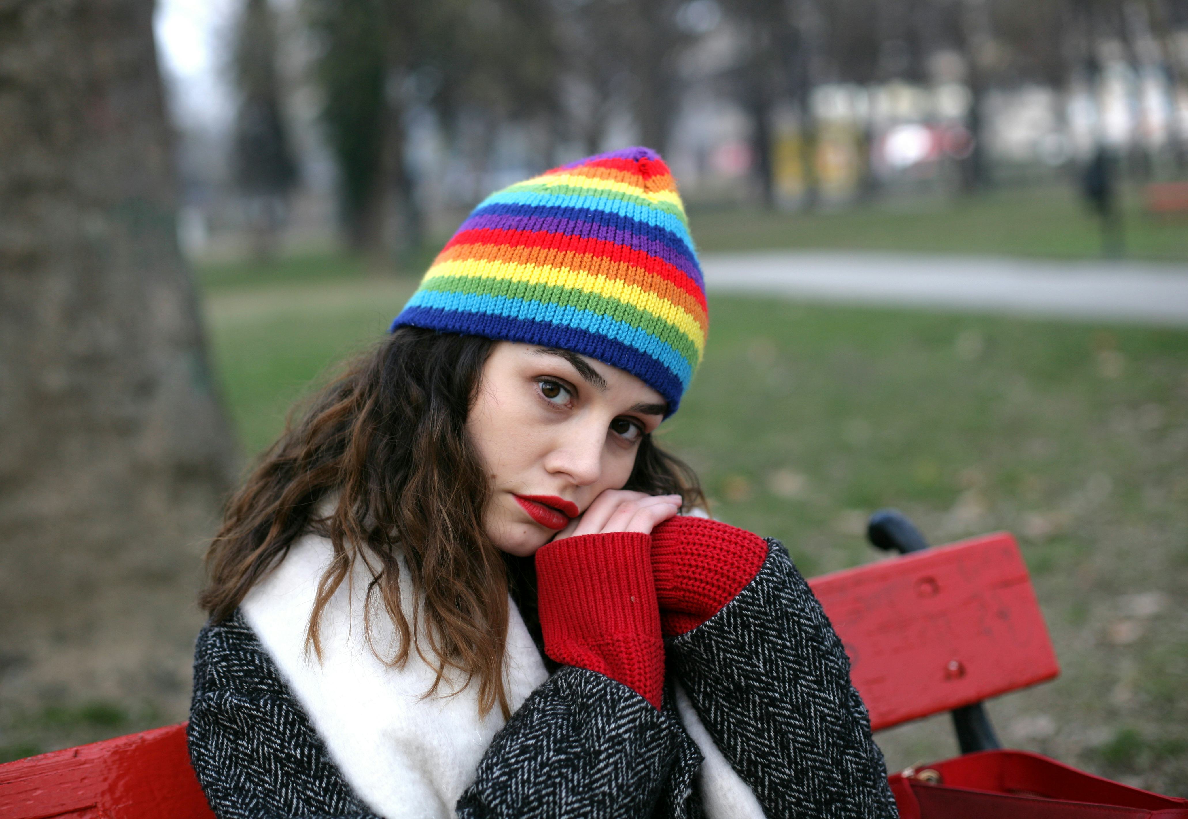 Woman portrait; lonely woman is sitting in a park bench with clasped hands in a winter season.