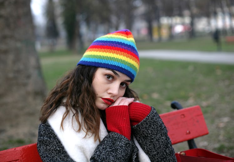 Woman portrait; lonely woman is sitting in a park bench with clasped hands in a winter season.