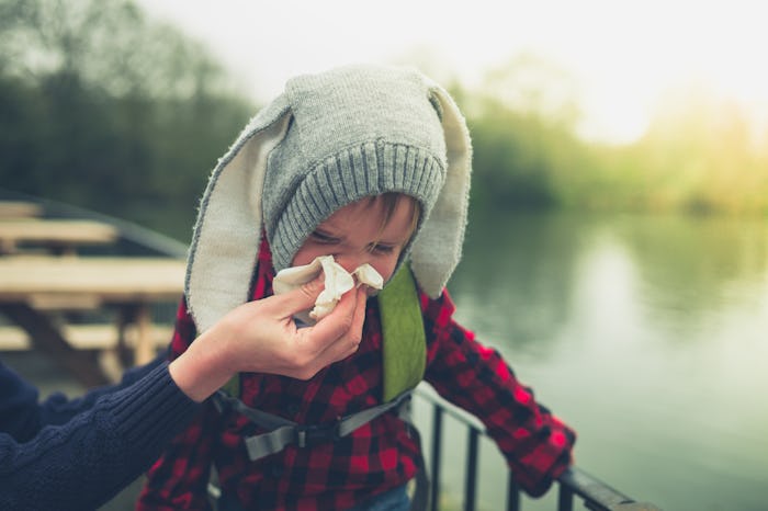 A mother helping her toddler son blow his nose