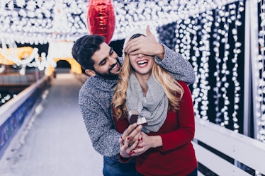 A man proposes to his girlfriend surrounded by twinkly lights outside on New Year's Eve.