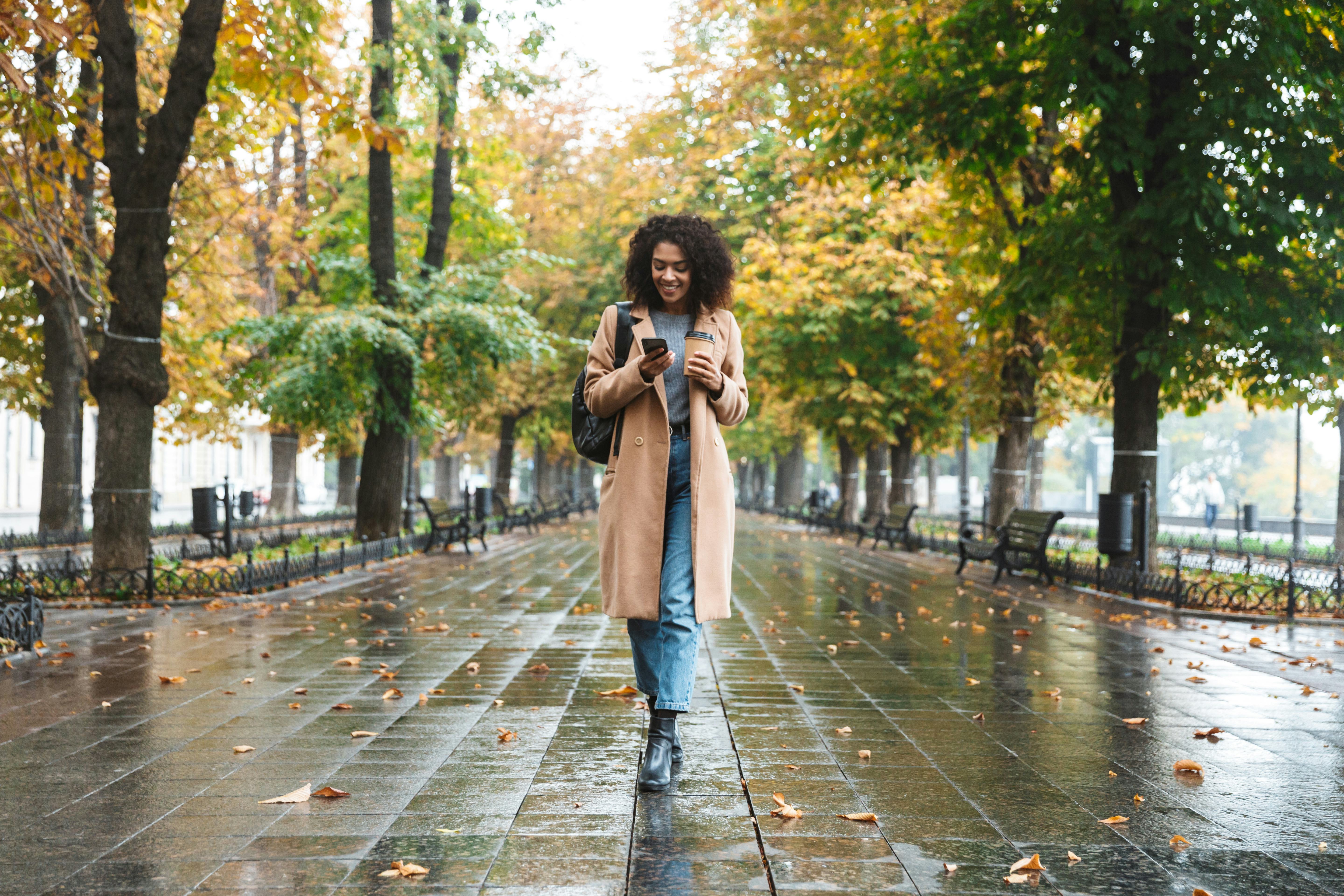 woman walking in rain looking at phone 