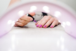 Hand paints the nails, gel purple, gel nail manicure through the lamp for manicure