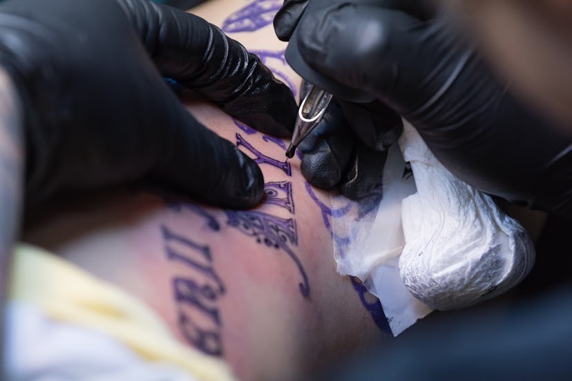 A woman getting a black script tattoo on her ribcage.
