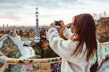 A woman takes a picture with her phone in Barcelona while on a Christmas vacation.