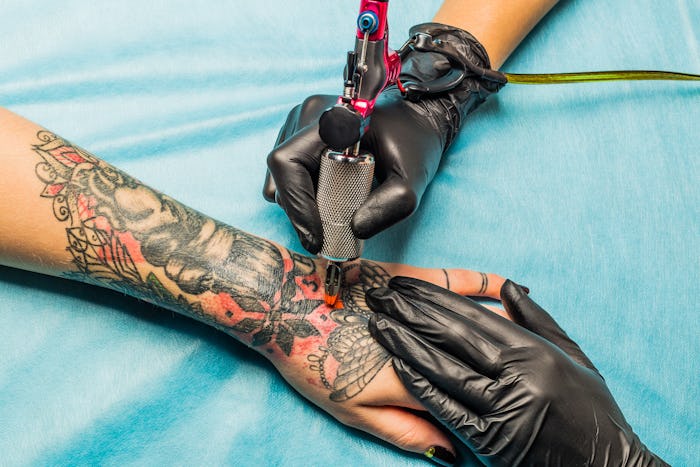 Close up tattoo artist inking design on a woman's wrist