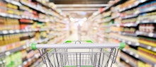 supermarket shelves aisle with empty shopping cart defocused interior blur bokeh light background